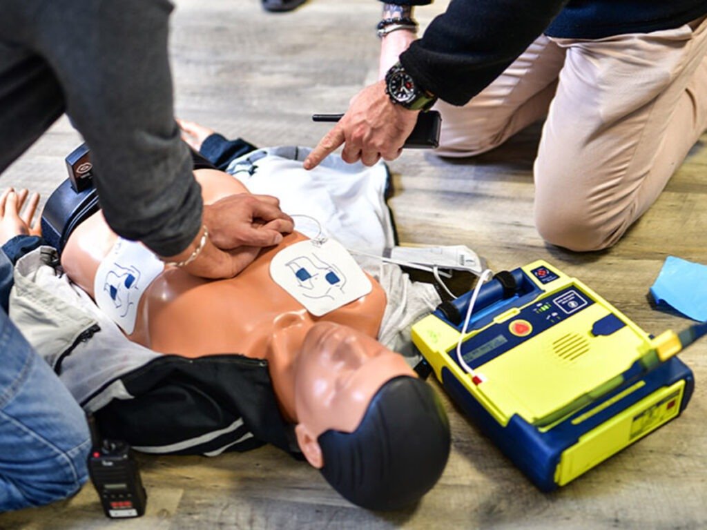 Homme faisant un massage cardiaque et pose un défibrillateur cardiaque.